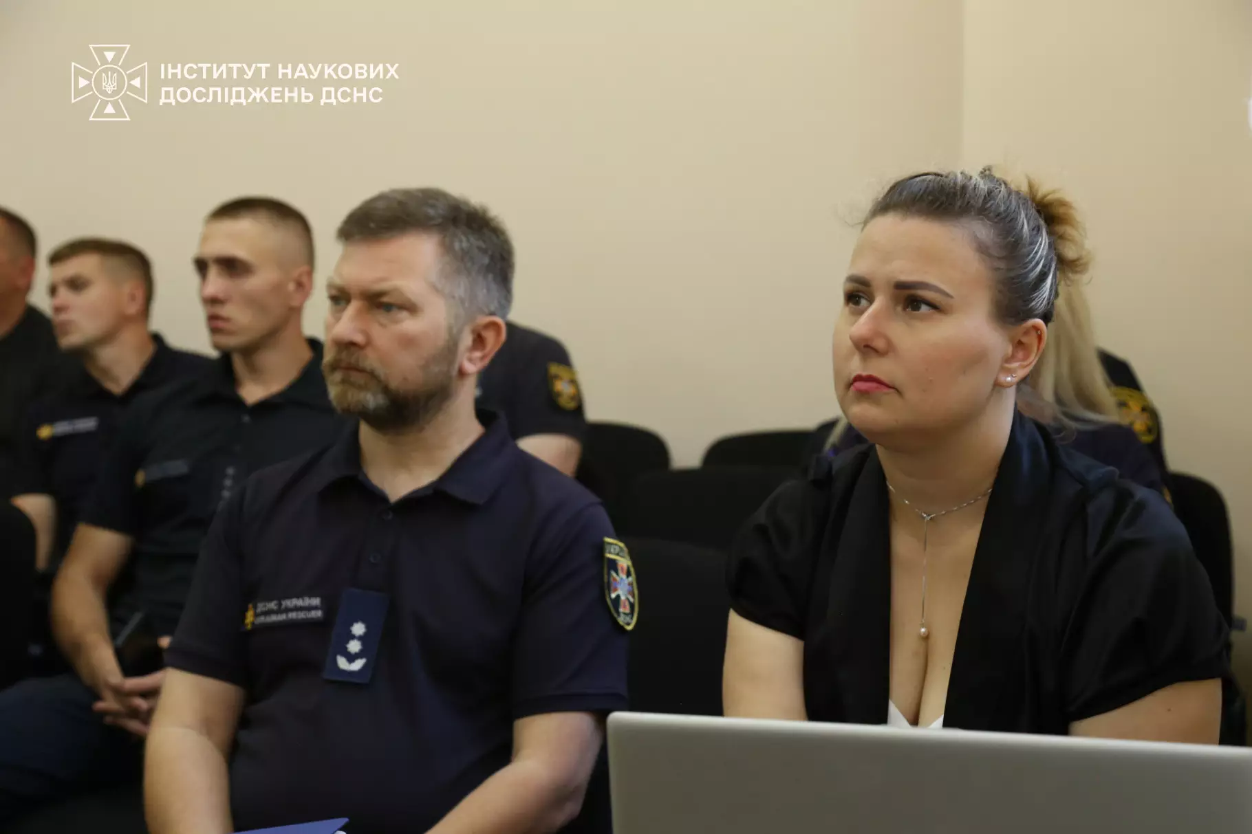 Учасники конференції в Інституті ДСНС. На передньому плані — жінка та чоловік у формі. Чоловік має шеврон із тризубом